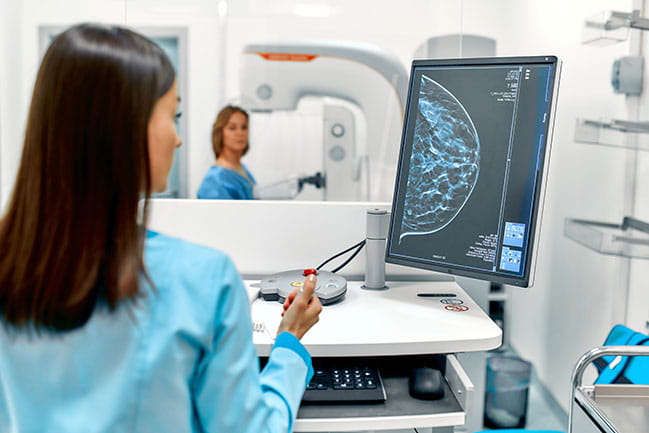 A technician conducts a mammogram.