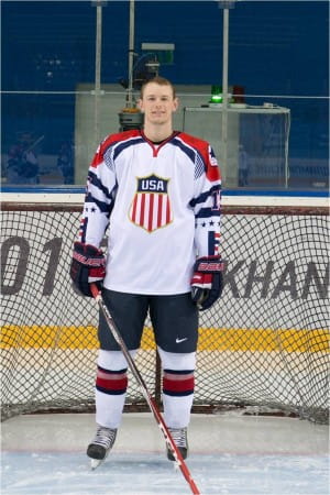 Max Finley in hockey uniform on the ice posing in front of a goal