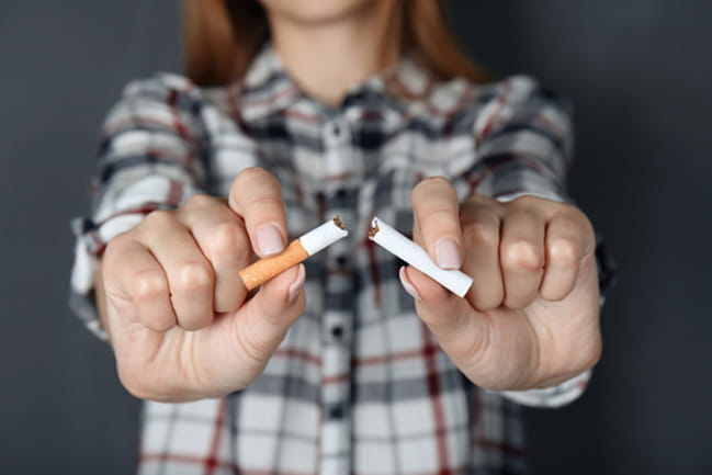 A woman breaks a cigarette in an effort to stop smoking.