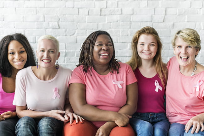 A group of breast cancer survivors gather around in support of one another.