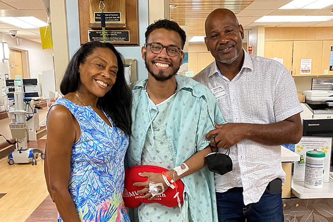 Dr. Cordy McGill-Scarlett between his parents. Everyone is smiling.