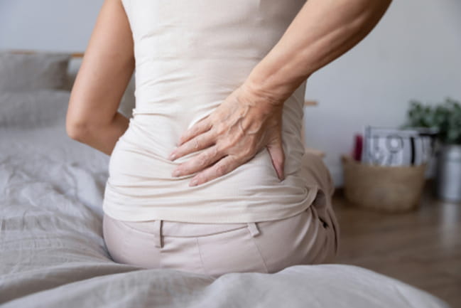 A person holds their back in pain from sciatica.
