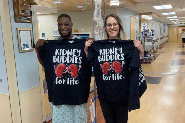 MUSC Health living donor Jennifer McGuire and transplant recipient Travis Snell hold up shirts that say "Kidney Buddies".
