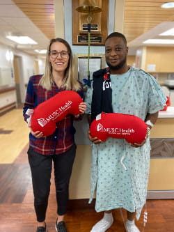 MUSC Health living donor Jennifer McGuire and transplant recipient Travis Snell hold MUSC Health kidney-shaped pillows.
