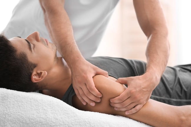 Person using their hands for manual therapy on a patients shoulder