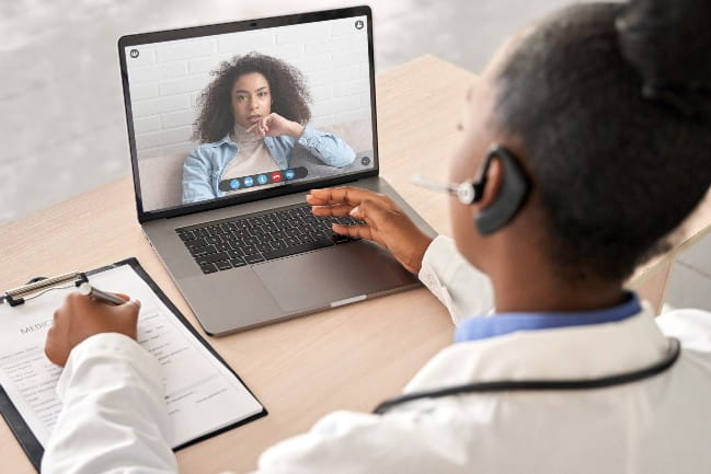 A doctor talks to a patient on a computer screen.