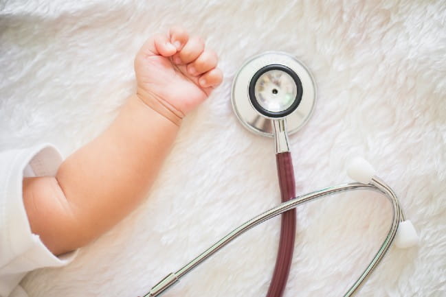 Arm of infant next to a stethoscope .