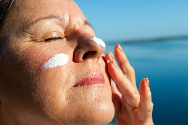 Person applyiing sunscreen to face