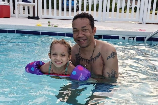 Jason Owens and his daughter Zoe smile as they play in the pool.