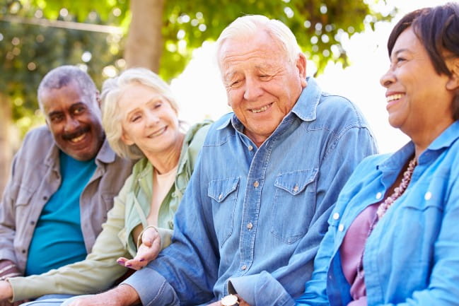 A group of four elderly individuals smiling and laughing together.