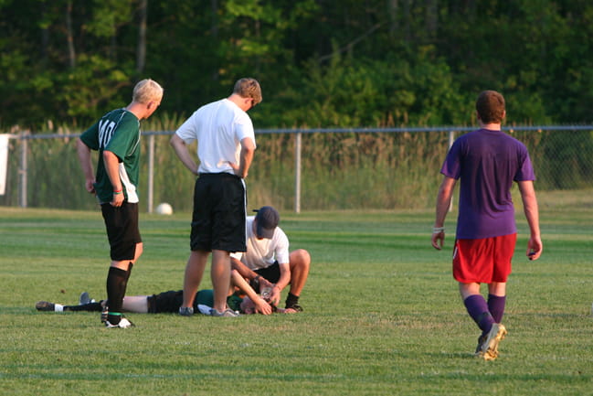 A professional tends to a soccer player likely injured with a concussion. 