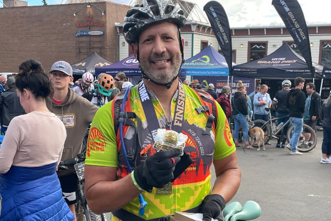 Zachary Sutton holding medal in bicycle gear.