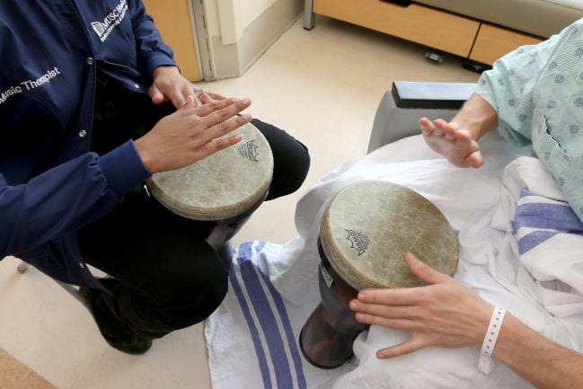 MUSC Arts in Healing music therapy with hospital patient at the bedside making music and drumming in music therapy