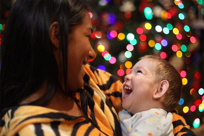 Image of mother and child in front of festive lights