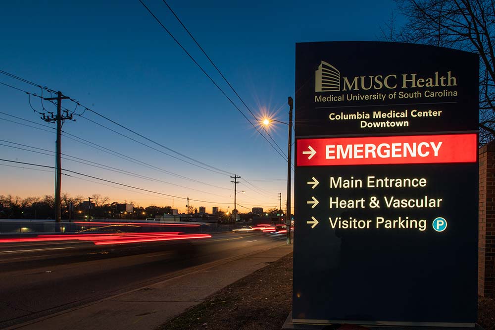 Night sky with a sign that says MUSC Health Downtown Columbia Medical Center. It also says Emergency in red and has an arrow that points right.